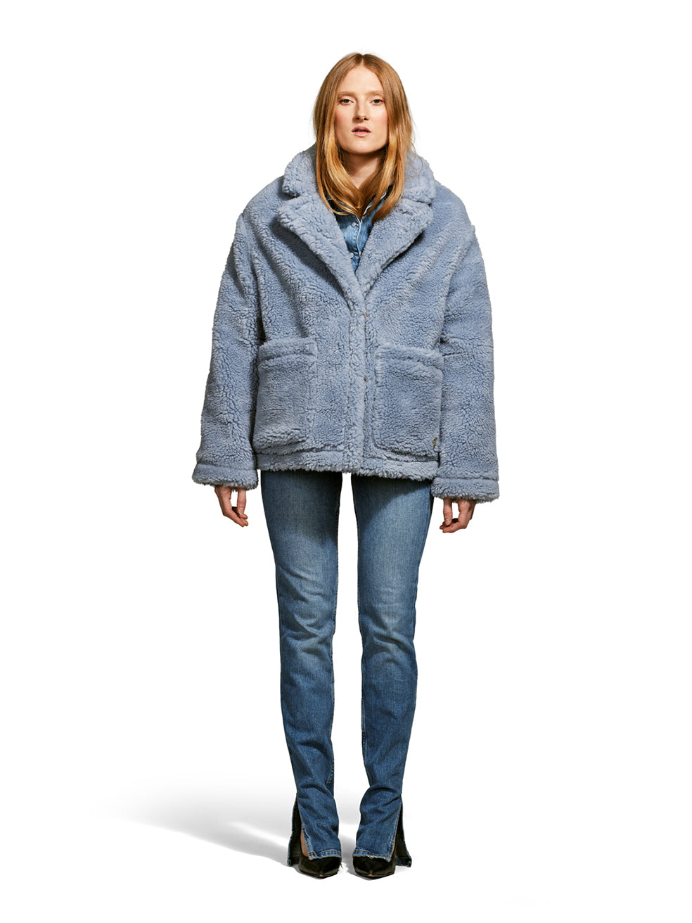 Model wearing the Robin, a hip-length teddy-inspired faux-fur sherpa shell in sky color from the front.